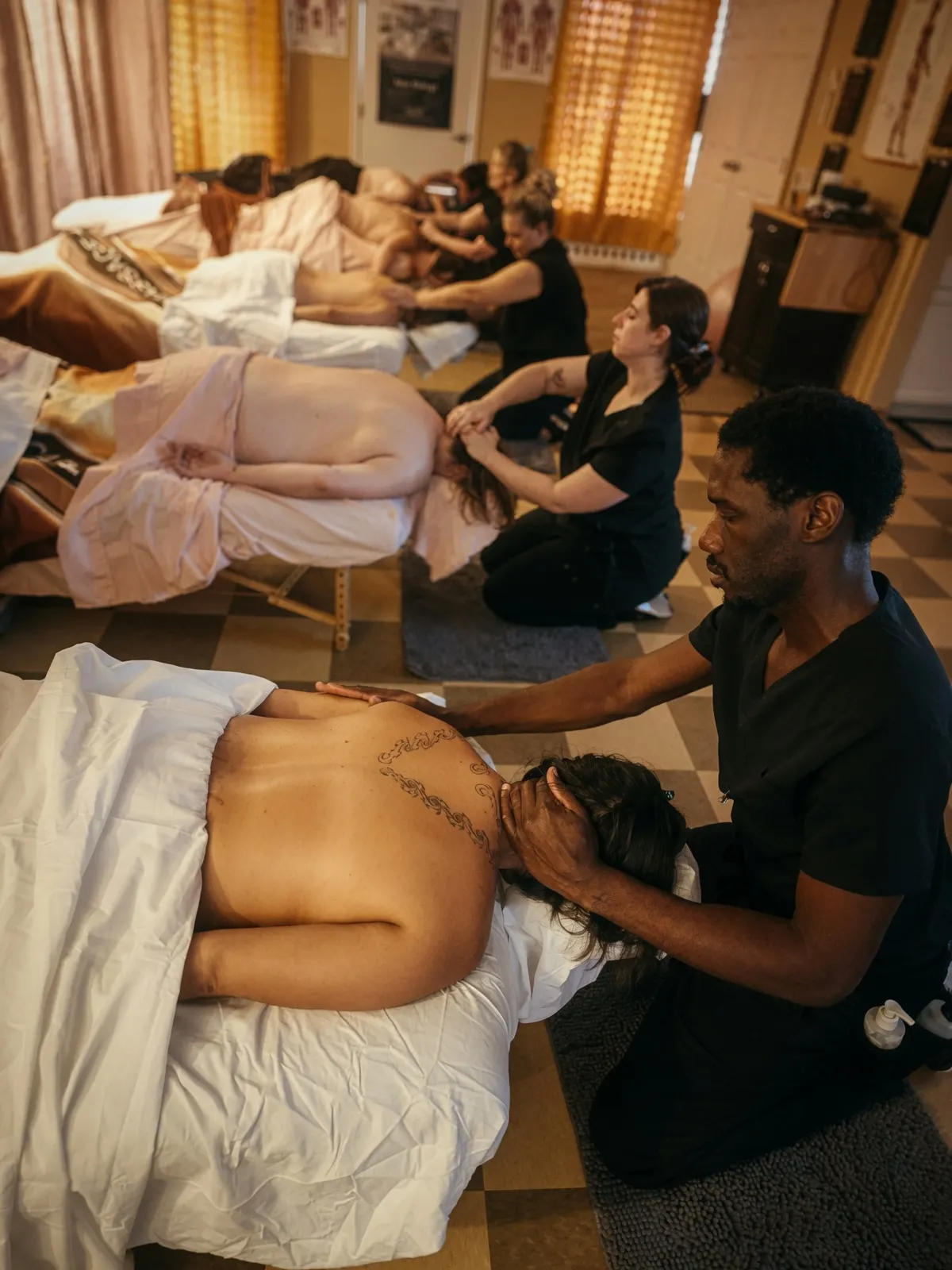 Male student massaging client head in busy clinic — Texas Massage Academy, Brownwood TX