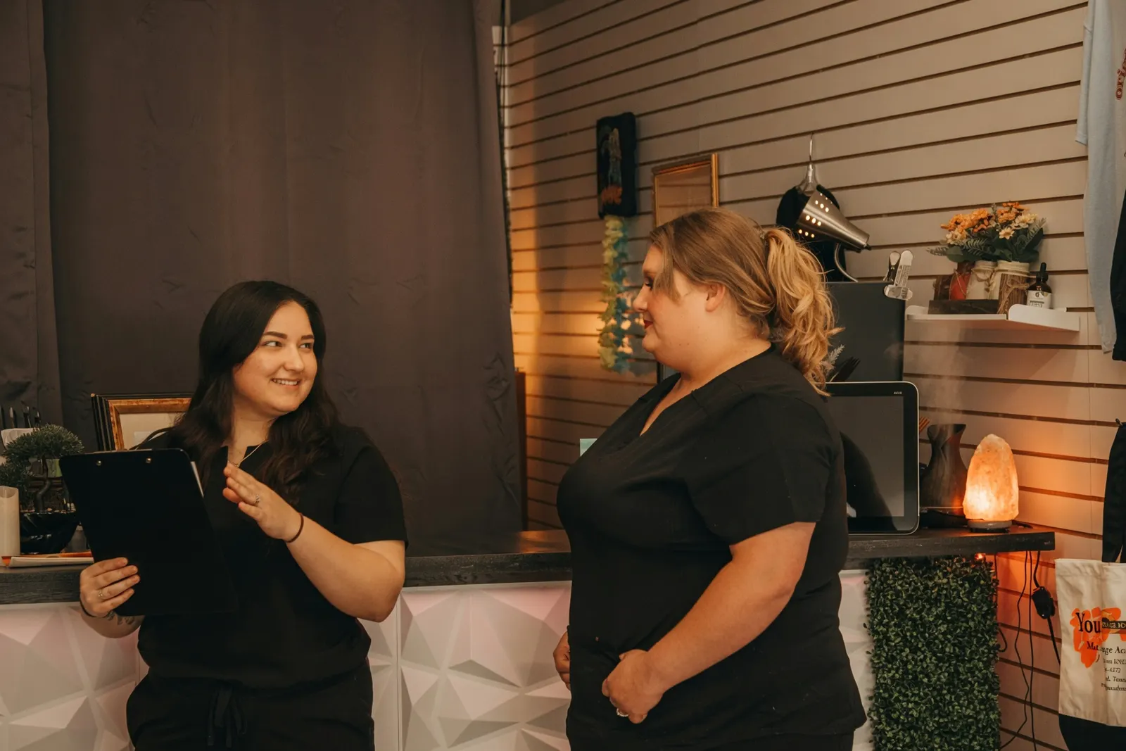 Students reviewing notes together at the clinic front desk — Texas Massage Academy, Brownwood TX