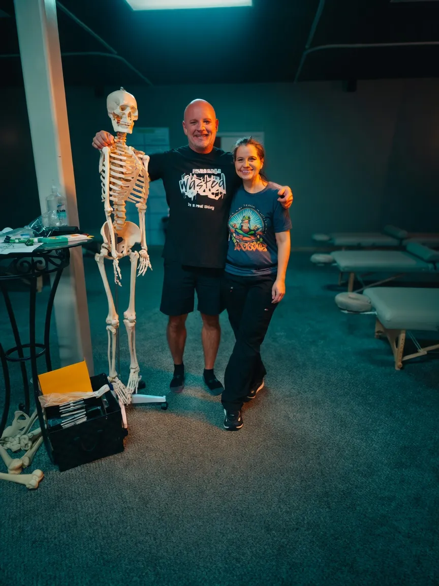 Instructor marking spinal landmarks on a client's back during a hands-on anatomy lesson