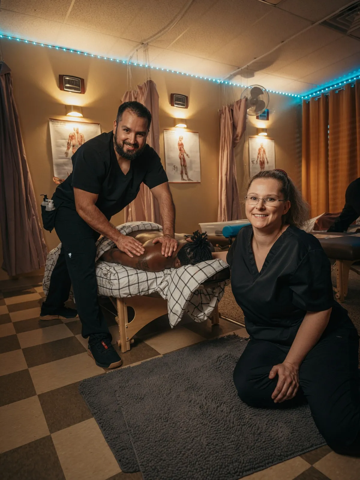 Instructor coaching a Texas Massage Academy student through a massage demonstration on a real client