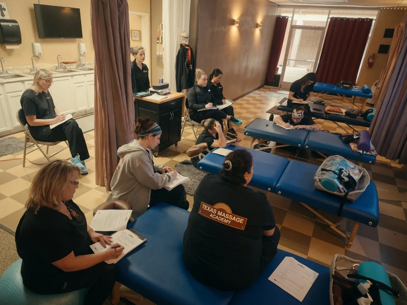 Texas Massage Academy students taking notes during a classroom lesson