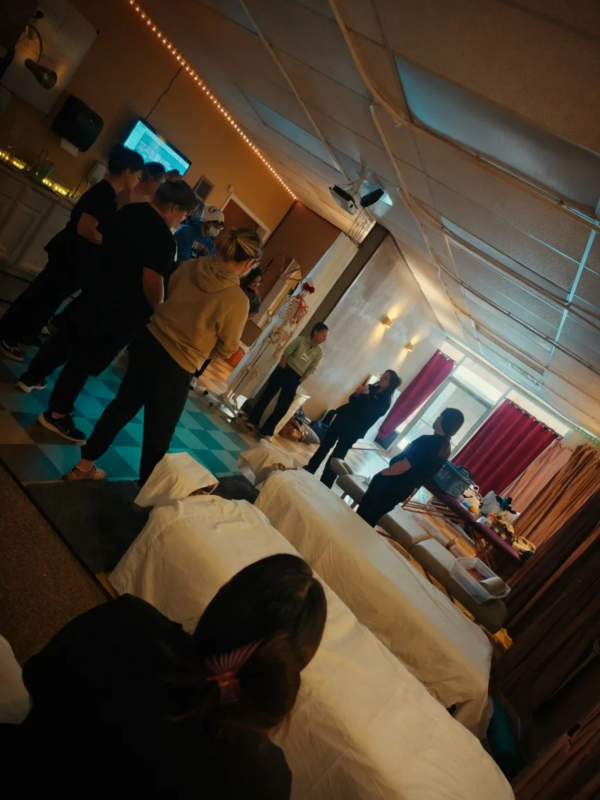 Wide view of the Texas Massage Academy classroom with students and massage tables