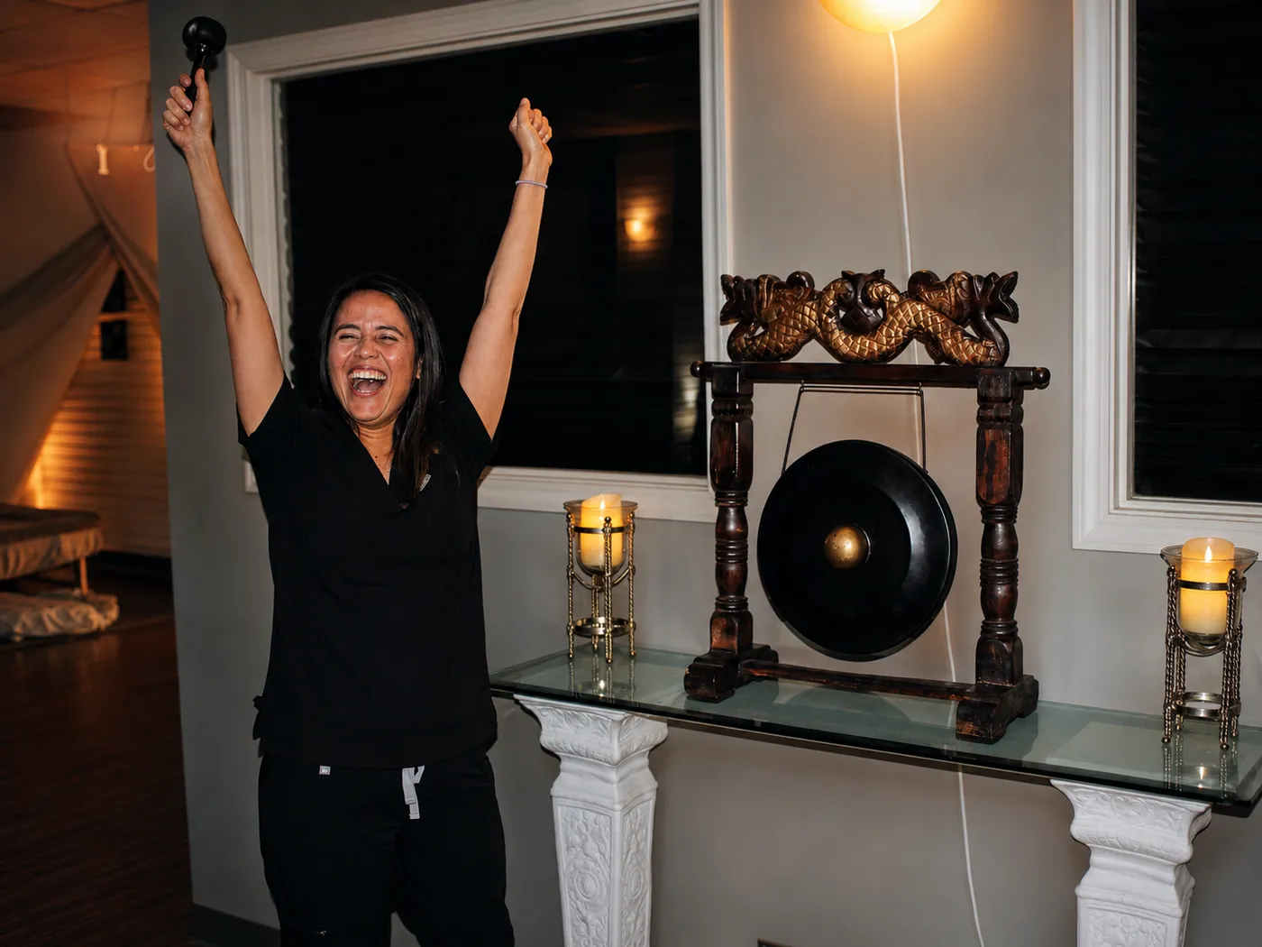 A Texas Massage Academy student celebrating by the ceremonial gong in Brownwood, Texas