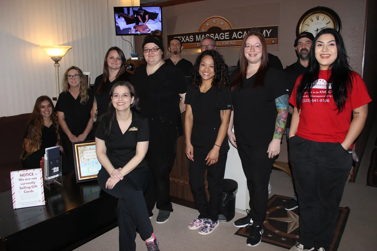 The Texas Massage Academy class and staff together under the sign at the Brownwood campus