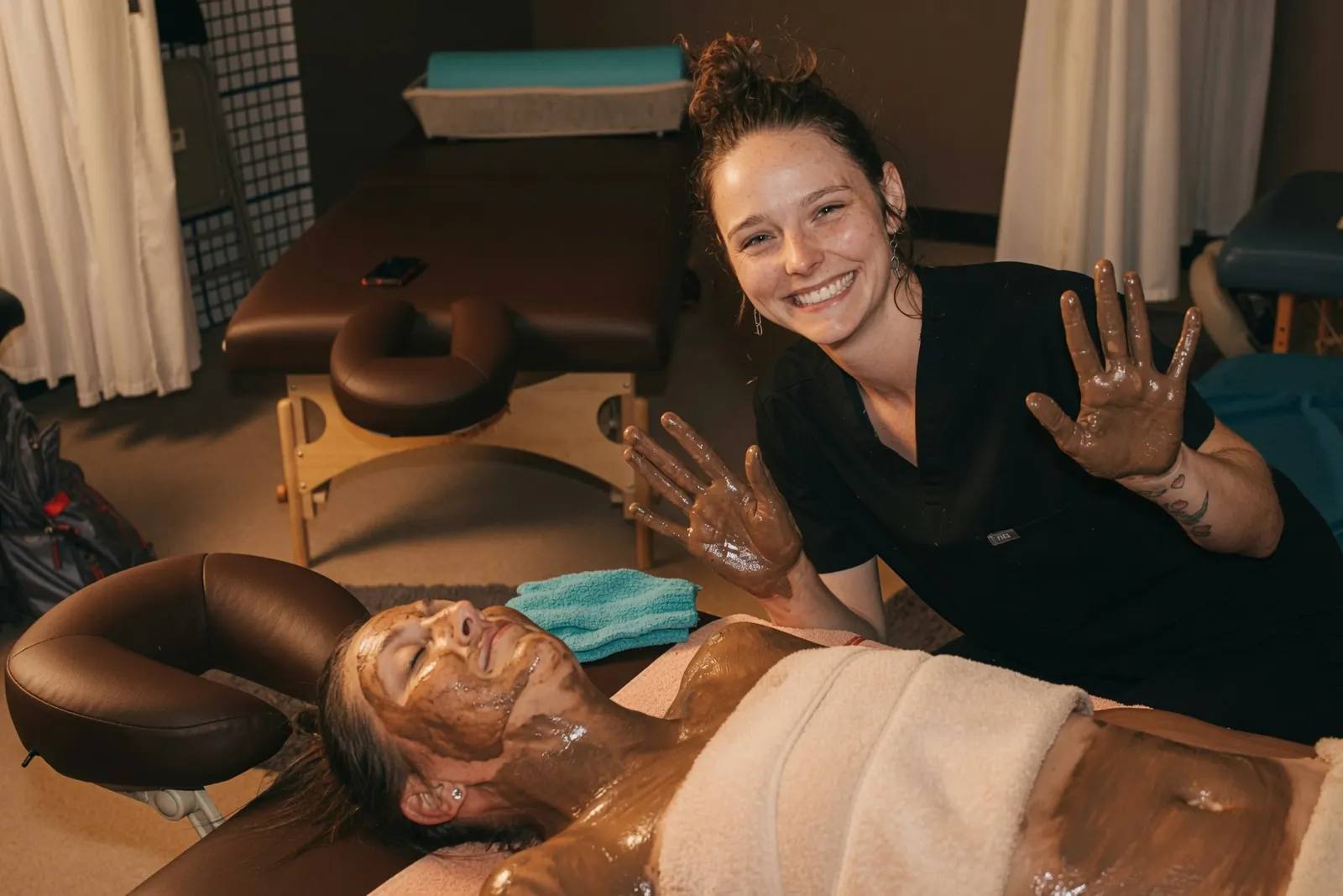 Smiling student therapist during a warm mud body treatment at the Texas Massage Academy day spa in Brownwood